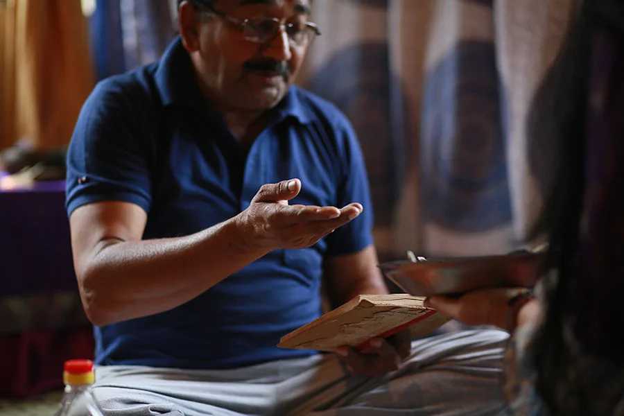 Guruji seated with a book of mantras, one hand raised