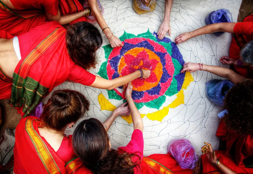 Seen from above: practitioners in red around a yantra of coloured rice