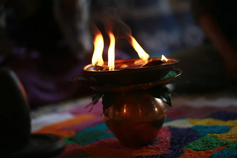 An oil lamp burning on a yantra of coloured rice